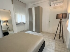 A bedroom with a bed, a wardrobe, a mirror, and a floor lamp. - Am'Arena Apartment - Sleeps 4, 300 meters from the Arena (Verona)