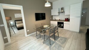 A modern kitchen with a dining area, a flat-screen TV, and a sofa in the adjacent living room. - Am'Arena Apartment - Sleeps 4, 300 meters from the Arena (Verona)