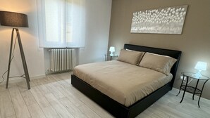 A modern bedroom with a bed, bedside tables, a floor lamp, and a radiator. - Am'Arena Apartment - Sleeps 4, 300 meters from the Arena (Verona)
