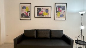 A black sofa with three framed abstract artworks on the wall above it. - Am'Arena Apartment - Sleeps 4, 300 meters from the Arena (Verona)