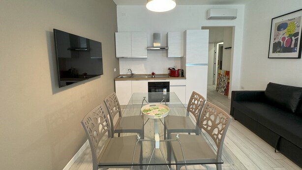 A modern kitchen with white cabinets, a built-in oven, and a dining area with a glass table and chairs. - Am'Arena Apartment - Sleeps 4, 300 meters from the Arena (Verona)