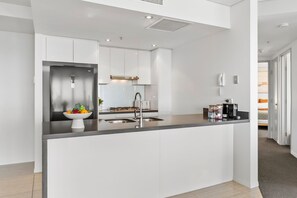 A modern kitchen with a central island, stainless steel appliances, and a white color scheme. - River Views from Level 43 | Free Parking, Pool & Gym (Brisbane City)