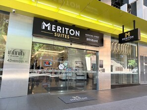 A hotel entrance with a glass facade, signage for Meriton Suites, and a visible street name sign. - River Views from Level 43 | Free Parking, Pool & Gym (Brisbane City)