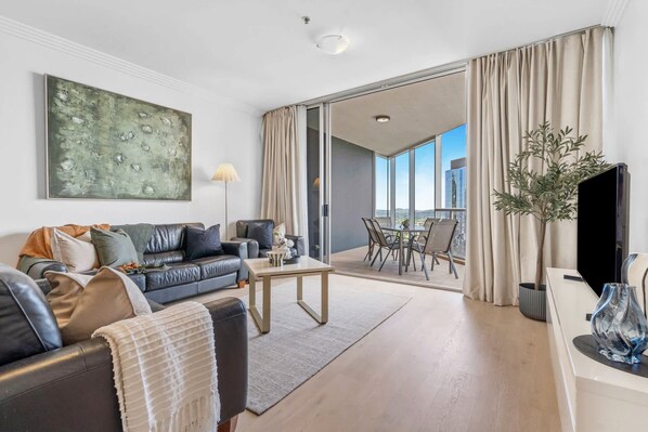 Een moderne woonkamer met een bank, salontafel en een eethoek met stoelen.