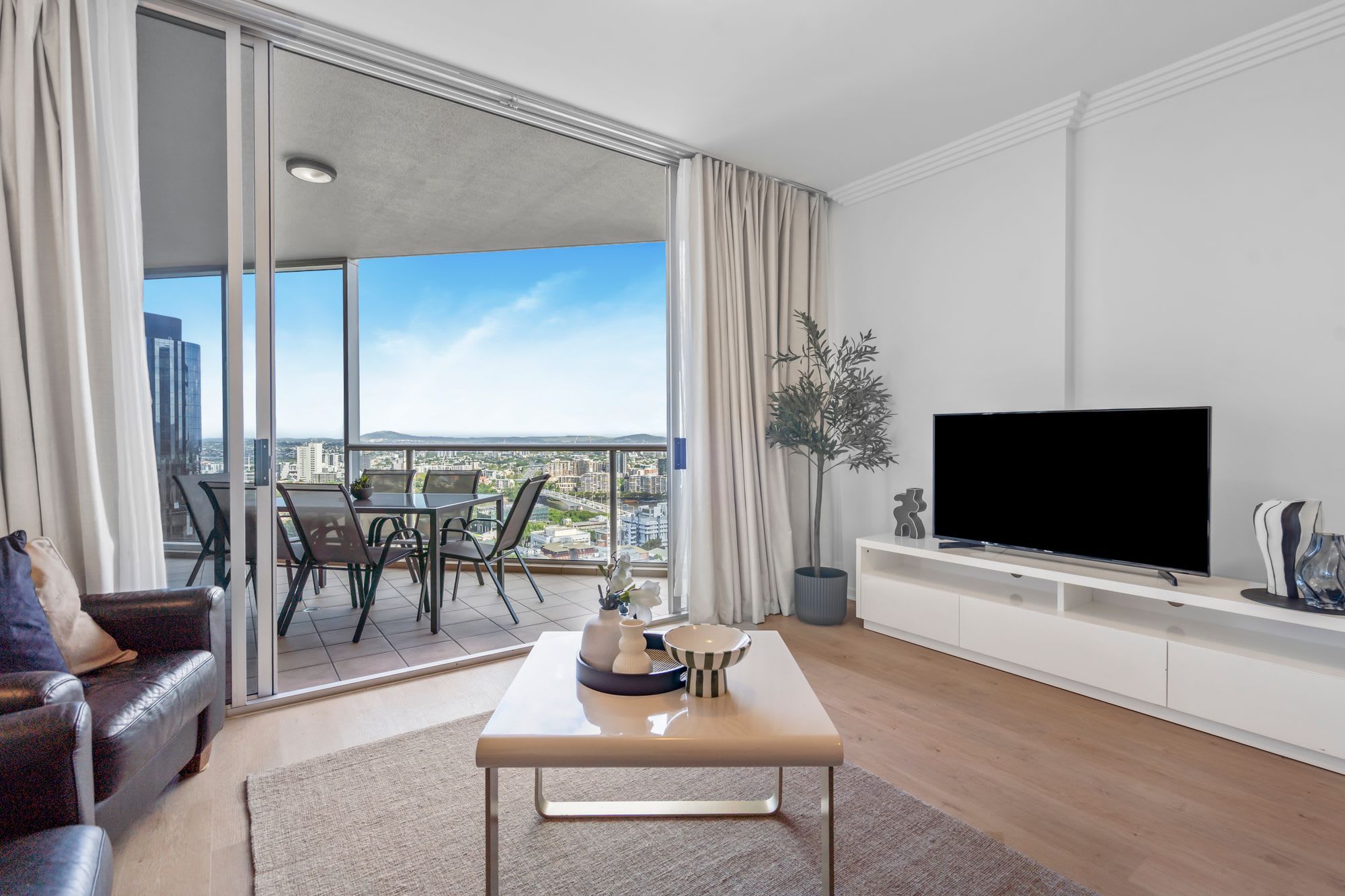 A modern living room with a large window, a flat-screen TV, a sofa, and a coffee table.