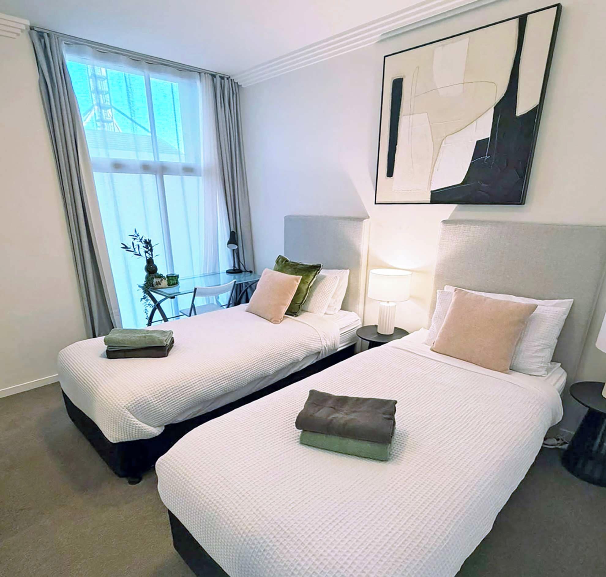 A hotel room with two beds, a desk, and a chair.