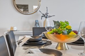 Una mesa de comedor lista, con frutero, copas de vino y cubiertos.