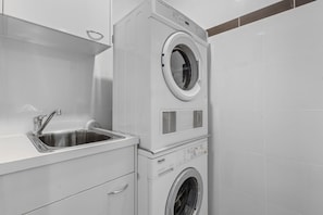 A compact laundry area with a built-in washing machine and a sink. - City Skyline from Level 37 | Free Parking, Pool & Gym (Brisbane City)