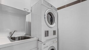 A laundry area with a washing machine and a sink. - City Skyline from Level 37 | Free Parking, Pool & Gym (Brisbane City)