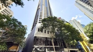 A tall, modern building with a reflective glass facade, surrounded by trees and other buildings. - City Skyline from Level 37 | Free Parking, Pool & Gym (Brisbane City)