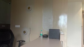 Un salón de conferencias con una larga mesa, sillas, una botella de agua, un teléfono e impresora pequeña.