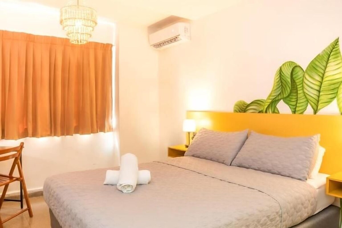 Ein Hotelzimmer mit Bett, Schreibtisch, Stuhl, Pflanze und einer Kristallleuchtre.