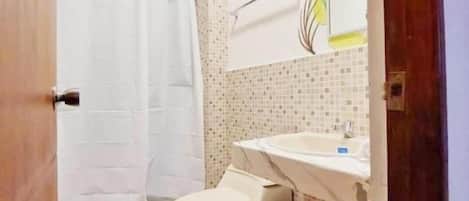 Un baño con inodoro, lavamanos y cortina de ducha.
