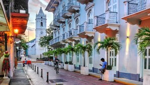 Una calle con edificios, una torre del reloj y palmeras.