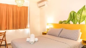 Una habitación de hotel con cama, escritorio, una silla, una planta y una araña.
