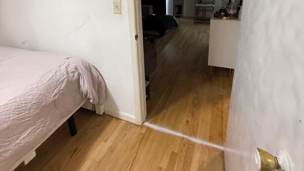 Een kamer met een bed, een witte muur en een houten vloer.