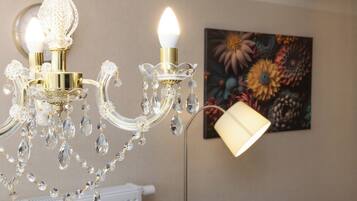Un lustre orné de décorations en cristal et une lampe fixée au mur.