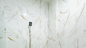 Un baño con paredes de mármol y zona de ducha.