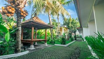 Um gazebo em um jardim tropical com palmeiras e um caminho de azulejos.