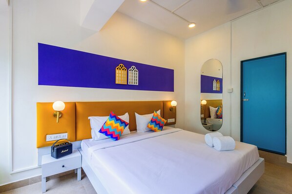 A hotel room with a bed, nightstand, radio, and a mirror. - goSTOPS PLUS Goa Candolim (Goa)