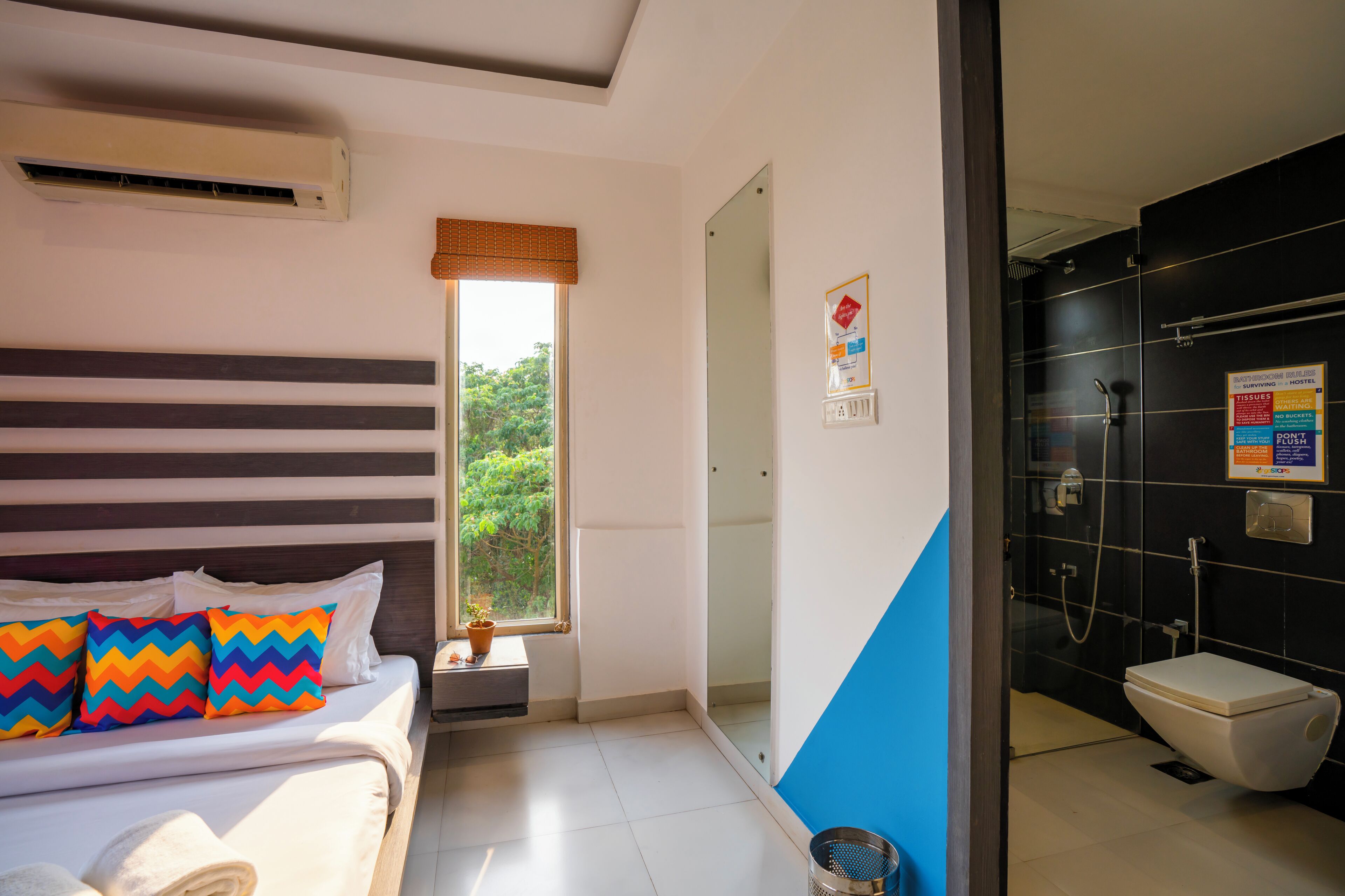 Una habitación de hotel con cama, ventana, baño con ducha y un cartel en la pared.