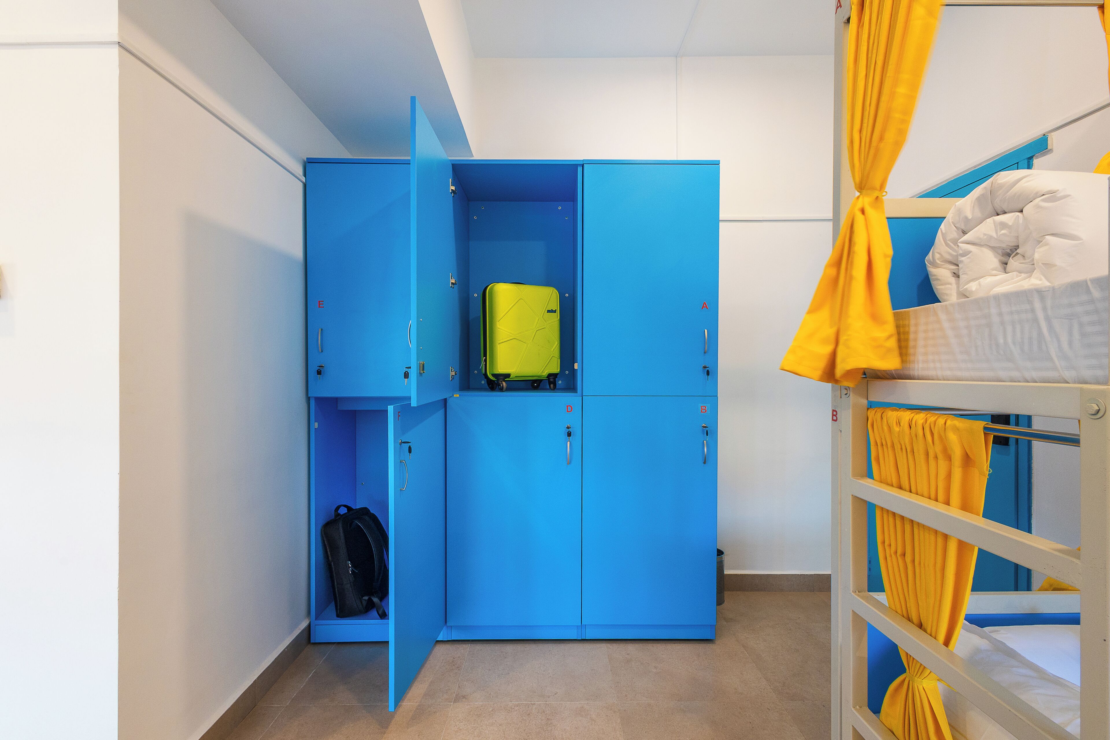 A room with a bunk bed, a blue wardrobe, and a suitcase on the floor.
