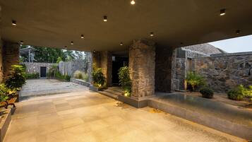 A covered outdoor area with stone walls, a paved floor, and potted plants.