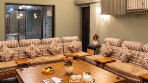 Een ruime woonkamer met een hoge plafond, een grote houten salontafel en een zithoek met banken.