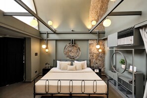 Um quarto moderno com uma cama grande, uma parede de destaque em pedra e um claraboia.