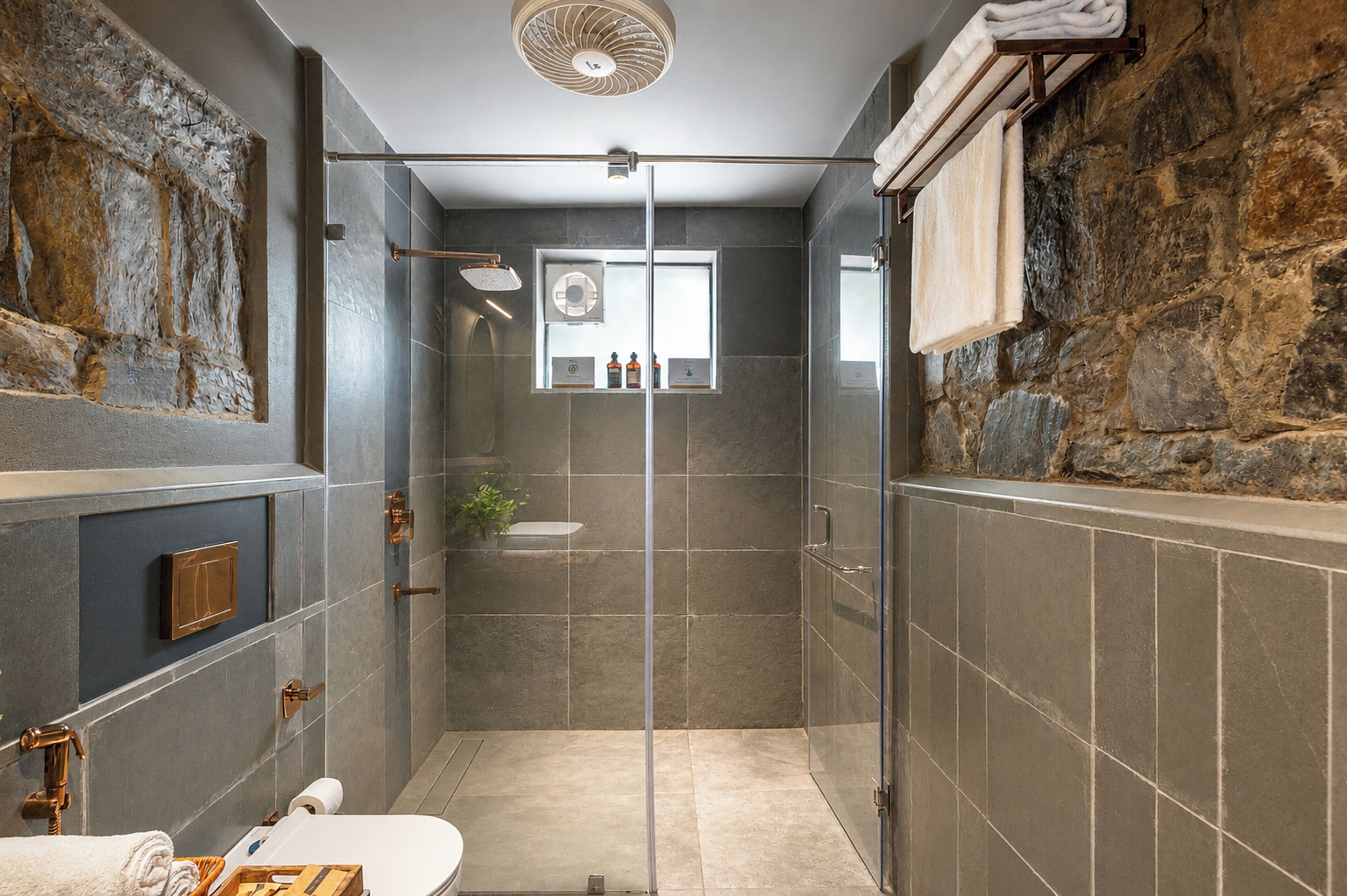 Et moderne badeværelse med en glasafskærmet brusekabine, toilet og håndvask.