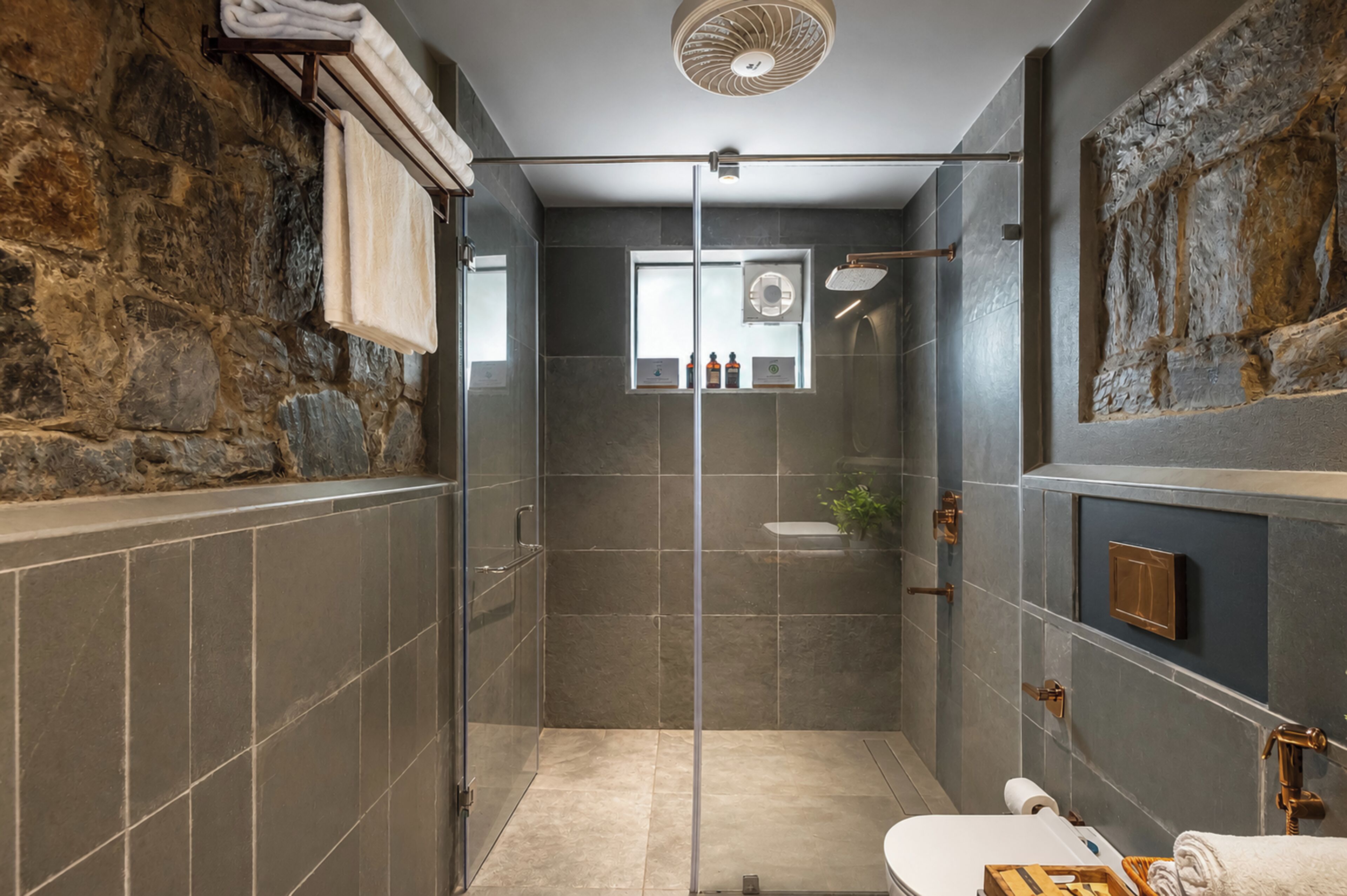 Een moderne badkamer met een glazen douchecabine, toilet en wastafel.