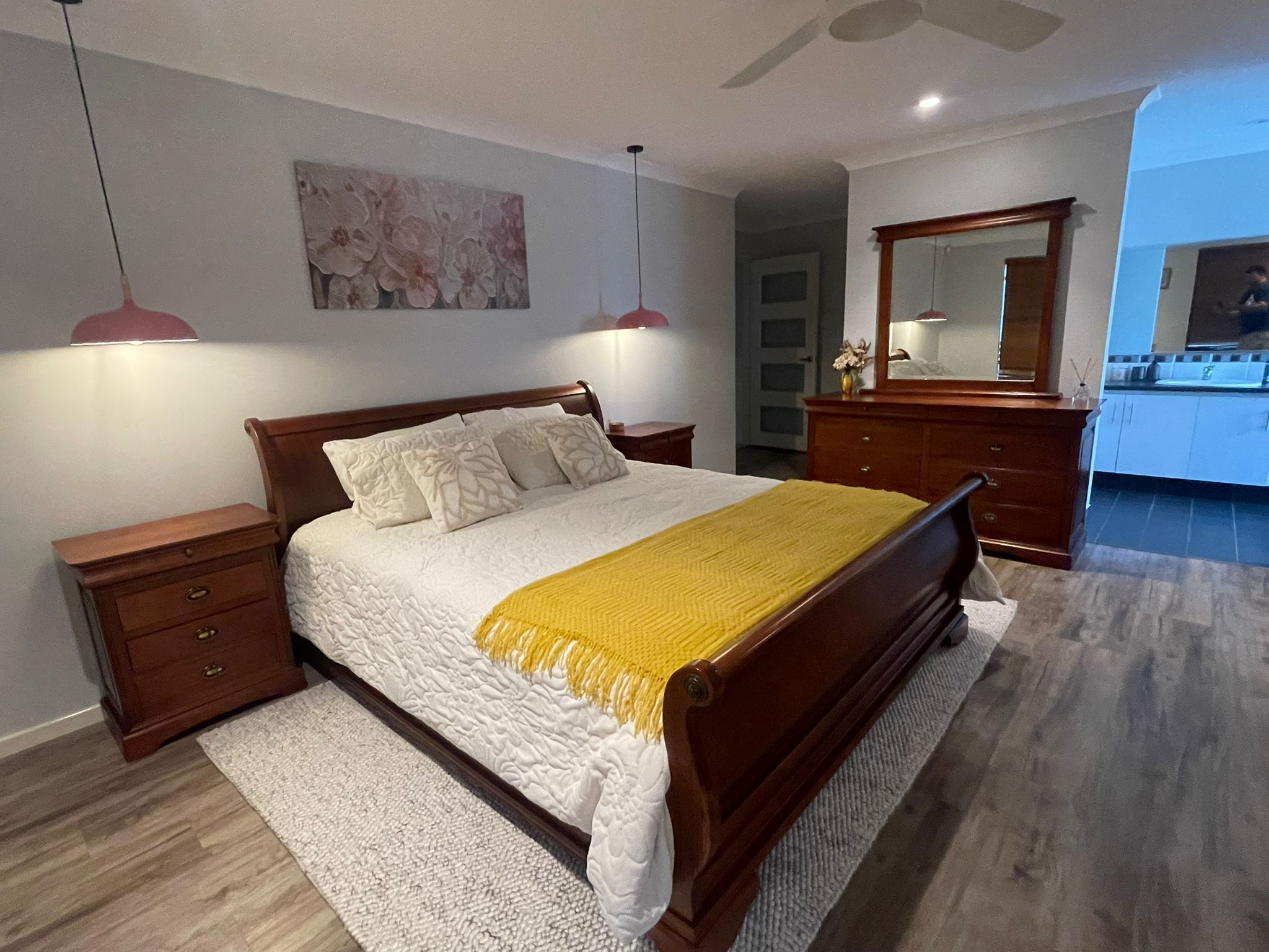 A bedroom with a bed, nightstands, a dresser, a mirror, and a painting on the wall.