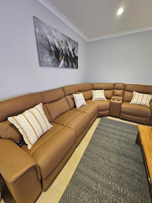 Uma sala de estar moderna com um sofá seccional marrom, um tapete cinza e um quadro na parede.