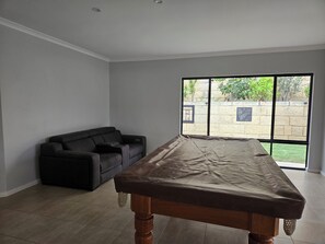 A room with a large window, a sofa, and a table. - Dawesville Family Beach Getaway – Steps from the Sand & Estuary (Dawesville)