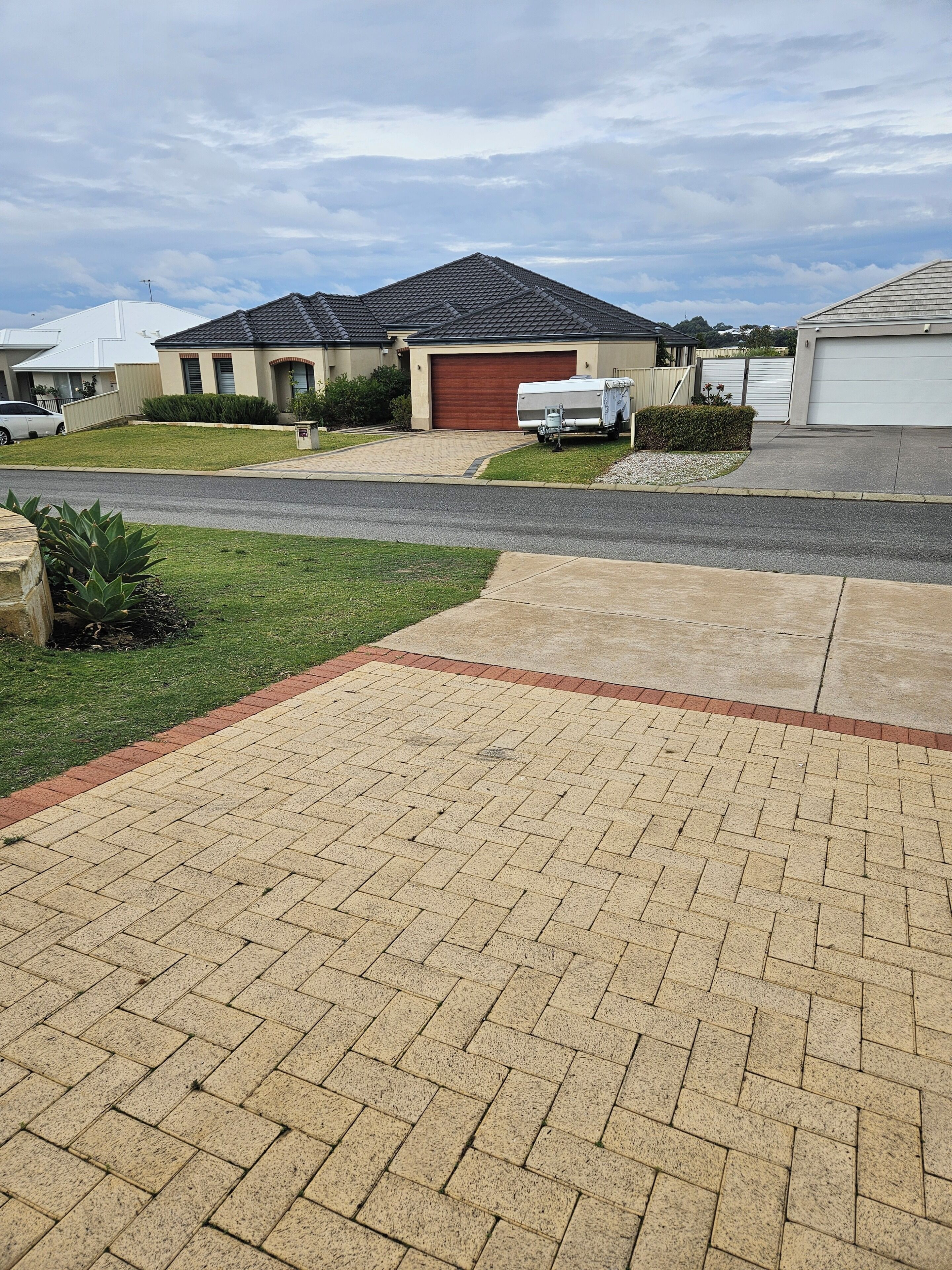 A residential driveway with a paved walkway leading to a house with a garage.