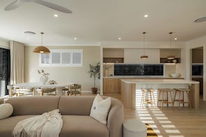 Una cocina moderna con una isla central, armarios de madera e iluminación colgante.