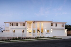 Una casa de dos pisos con fachada blanca, cerca blanca y garaje.