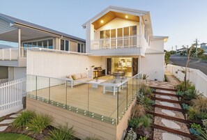 Una casa de dos pisos con un balcón, una terraza y un pequeño jardín.