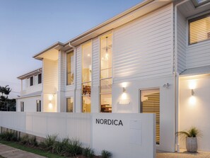 A modern two-story building with a white exterior, large windows, and a visible nameplate reading 'NORDICA'.