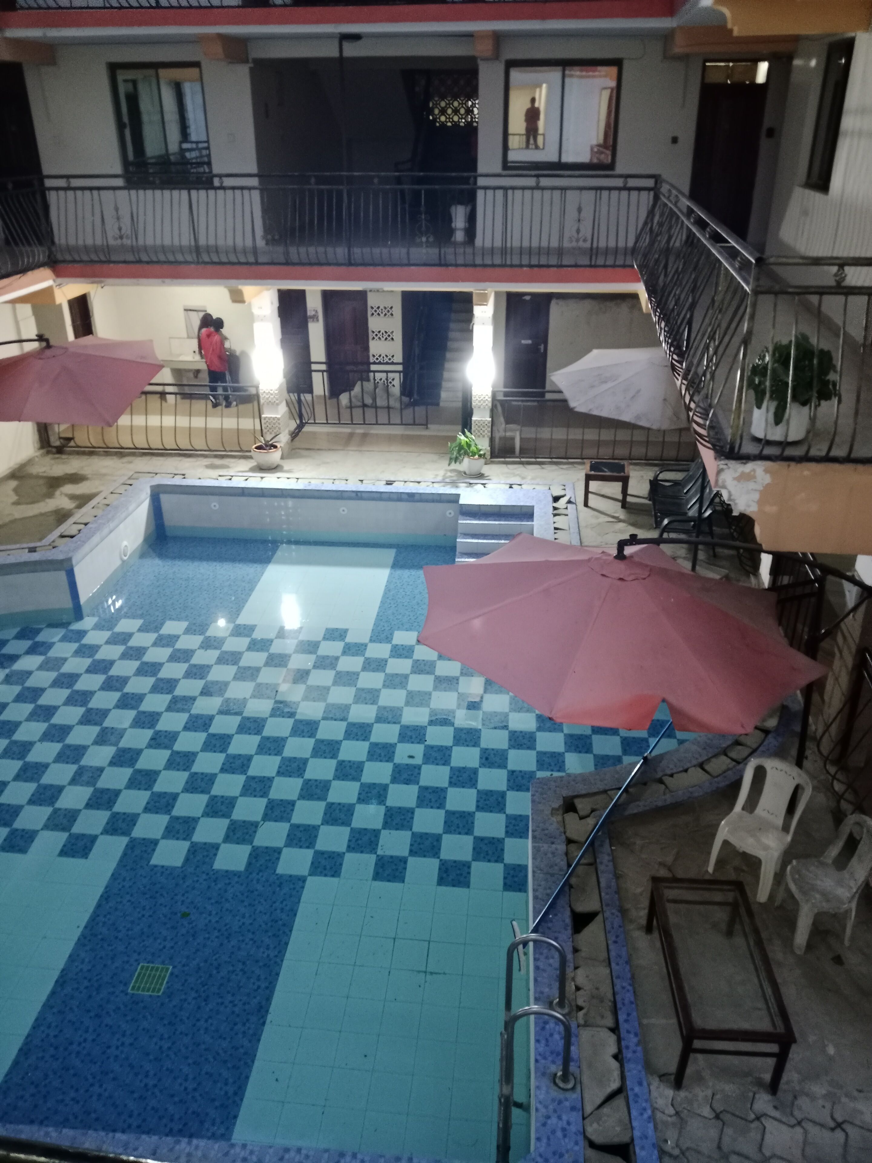 Un área de piscina con baldosas de cuadros, una piscina pequeña y una escalera que lleva a un nivel superior.