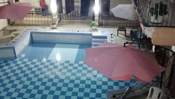 Un área de piscina con baldosas de cuadros, una piscina pequeña y una escalera que lleva a un nivel superior.
