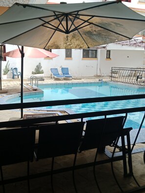 A pool area with lounge chairs and an umbrella. - Cozy studio apartment in quaint Mtwapa with an AC and Swimming Pool (Mtwapa)