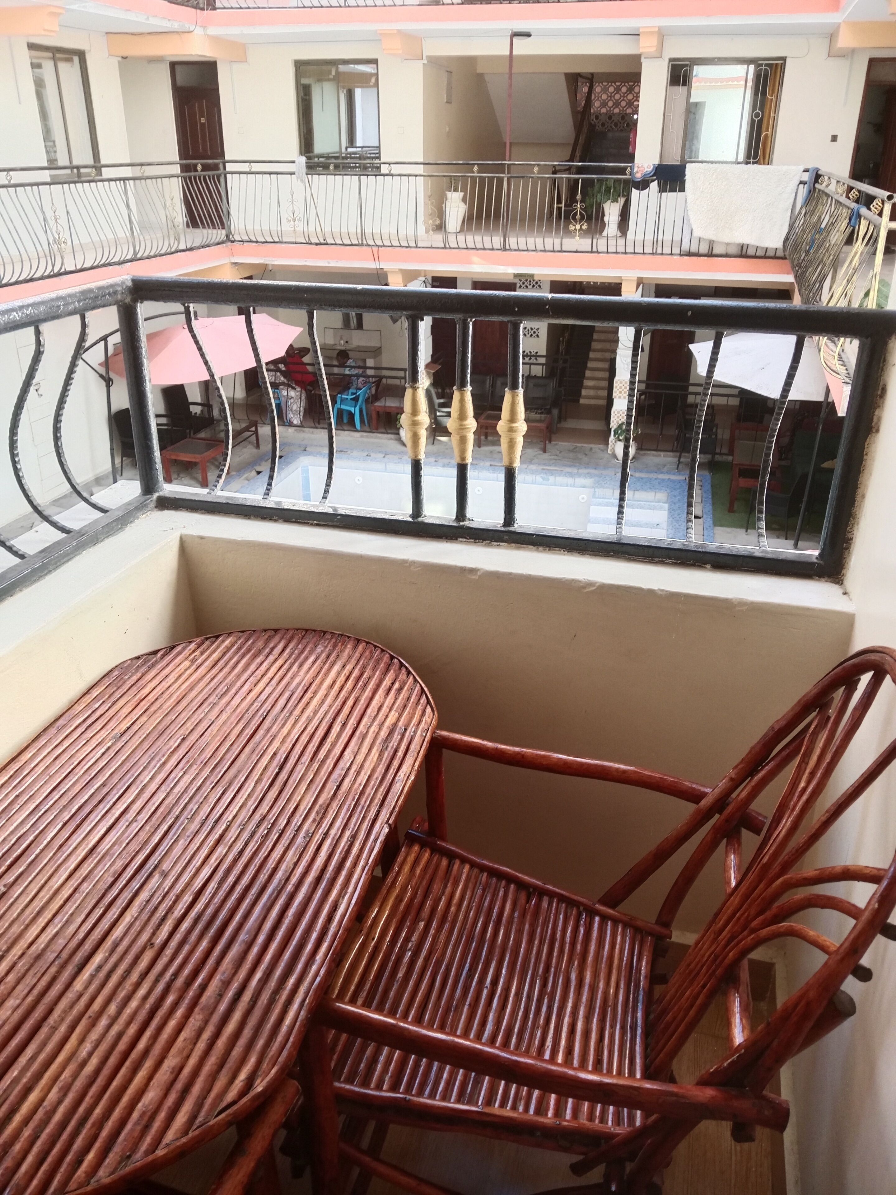 Ein Balkon mit Tisch und Stühlen, Blick auf die Straße, und ein Gebäude mit Balkonen.