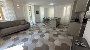 A modern apartment with a living area, dining space, and kitchenette. - Baveno Rose Apartment 1 (Baveno)