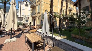 Een terras met tafels, stoelen en parasols, tegen een stenen muur.