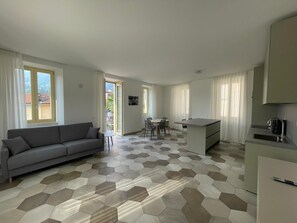 A modern apartment with a living area, dining space, and kitchenette. - Baveno Rose Apartment 3 (Baveno)