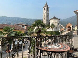 A balcony with a patterned table, a clock tower, and a church in the background. - Baveno Rose Apartment 3 (Baveno)
