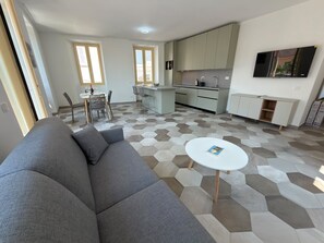 A modern living room with a grey sofa, a white coffee table, and a hexagonal patterned floor. - Baveno Rose Apartment 3 (Baveno)