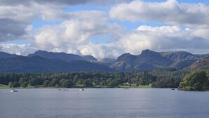 Un lago con barcos, rodeado de colinas y montañas boscosas.