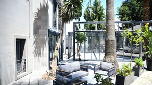 An outdoor seating area with modern furniture, surrounded by glass walls and potted plants. - MyElla Marina Hotel (Bodrum)